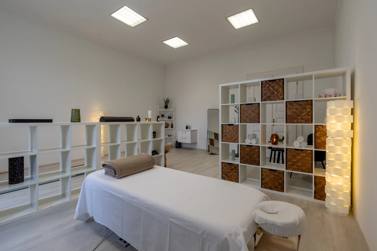 A quiet treatment room with a massage table and neatly arranged shelves